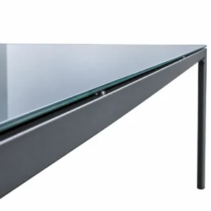 Close-up of the glass tabletop edge mounted on a dark grey iron frame