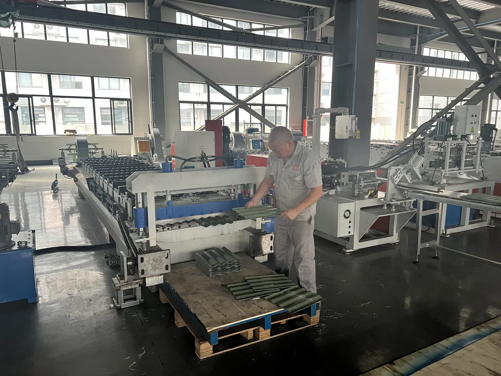 Worker checking corrugated panels for galvanized steel raised garden beds at a roll-forming line